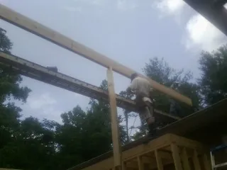 Carpenter setting a ridge beam over a new addition frame in Edgerton