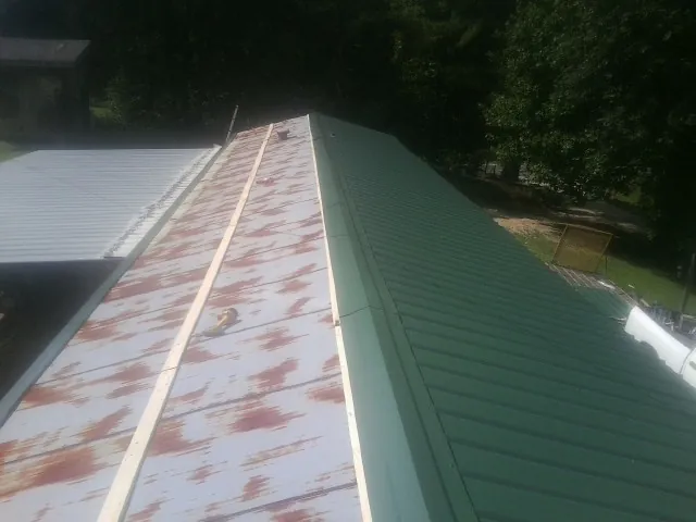 Old rusted panels beside newly installed green metal roofing — Wind Damage Roof Repair by Roofing Brothers in Edgerton