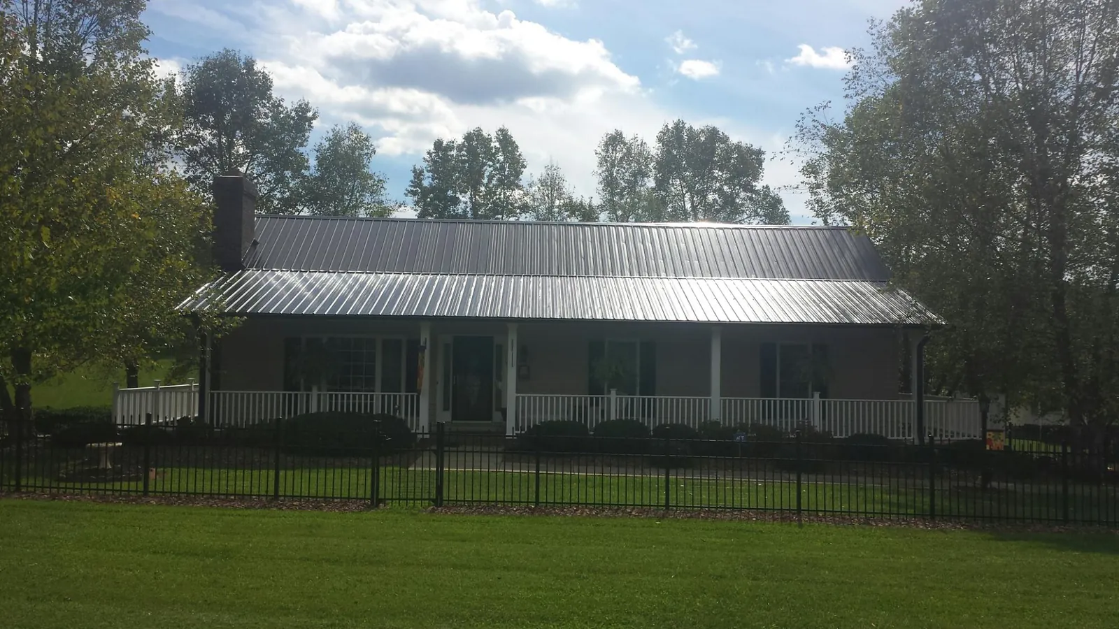 Gray metal roof on a brick ranch with a full width front porch — Gutter Guard Installation work by our crew in Edgerton